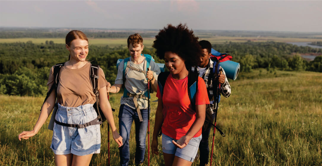 Four friends hiking through a scenic landscape with backpacks on small group budget safari game drives in Masai Mara.