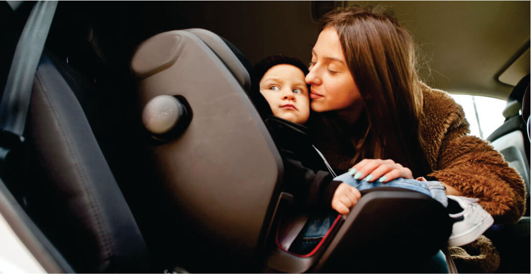 Woman adjusting a child in a car seat inside a vehicle