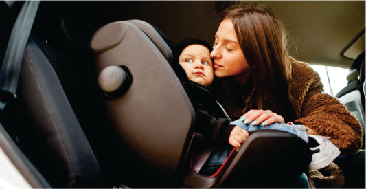 Woman adjusting a child in a car seat inside a vehicle