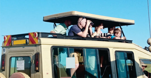People on an open-top vehicle with a clear blue sky, on 3-Day Masai Mara jeep joining safari game drives