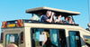 People on an open-top vehicle with a clear blue sky, on 3-Day Masai Mara jeep joining safari game drives