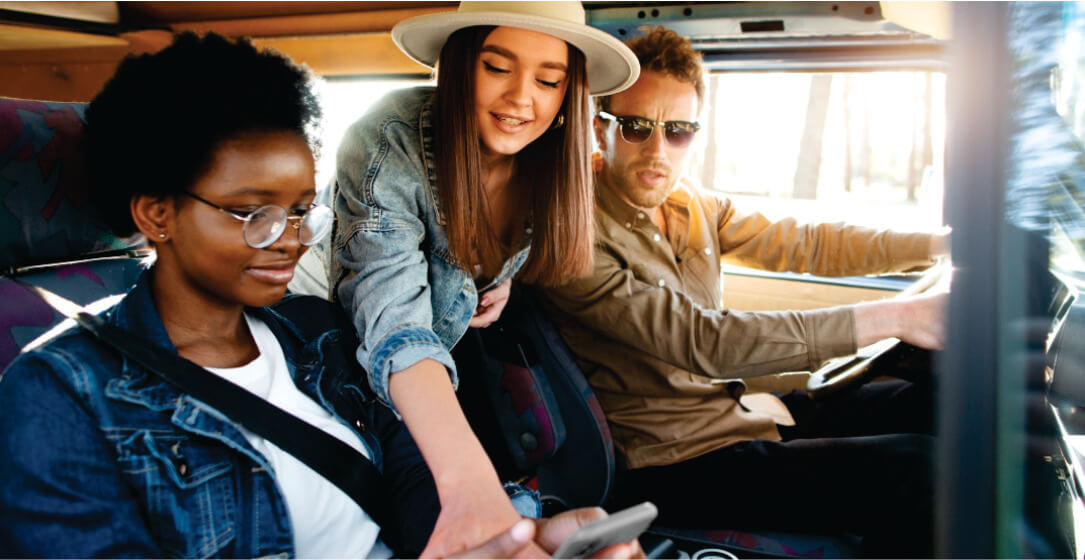 Three people in a car, with one using a smartphone.