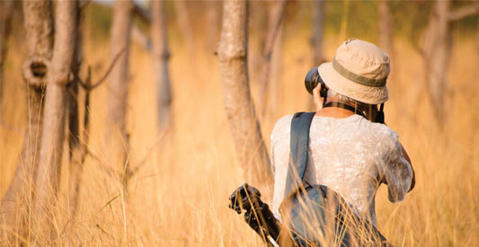 Person walking through tall grass with a hat and backpack in a natural setting, on solo joining safari game drives in Masai Mara 
