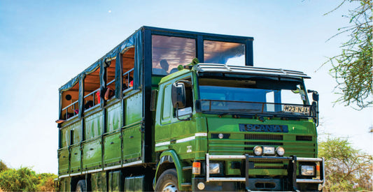 Green truck converted into a mobile home with large windows, parked outdoors for Mara safari vehicle rental