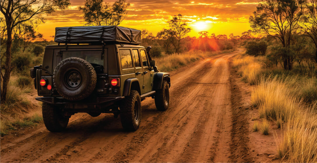 Transfer jeep on a dirt road with a sunset in the background