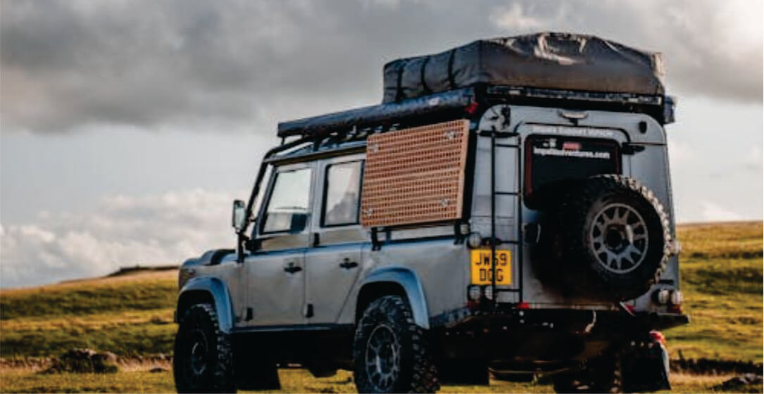 Off-road vehicle with roof rack and storage boxes on a grassy field