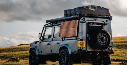 Off-road vehicle with roof rack and storage boxes on a grassy field