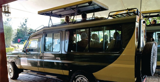 People inside a green 4x4 safari jeep vehicle for hire with an open roof, watching on a sunny day