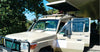 Beige jeep safari vehicle with open roof and roof rack parked at a Nairobi Hotel, awaiting to transfer guests from Nairobi to Ol Pejeta Conservancy Kenya.