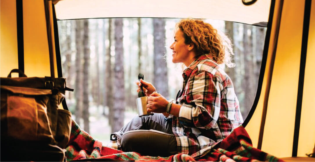 Woman sitting inside a camper van on rental with a forest view
