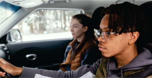 Two people sitting inside a transfer car with a focus on the driver.